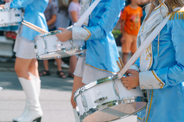 Close-up of female hands drummers are knocking in the drum of their sticks. Majorettes in the parade