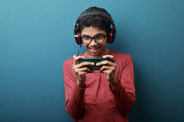 Young boy wearing headphones plays games a smart phone