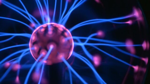 Plasma ball lamp with moving filaments extending between inner and outer spheres. Close up view of multiple colored beams, waves radiating from center. 4K UHD 2160p ultra high definition.

