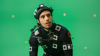 Portrait of an Actor Wearing Motion Caption Suit and Head Rig Posing with Green Screen Background....