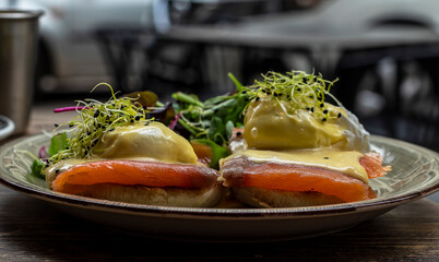 Selective focus. Delicious breakfast or brunch, egg benedict with smoked salmon, and green lettuce