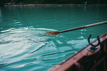 close up paddle oar in the water. Wooden rowing boat on a lake or river.