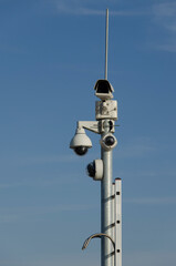 Electronic cctv security camera, surveillance camera on top of pole on blue sky background
