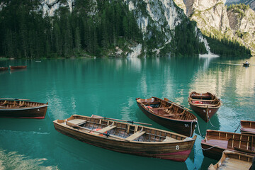 Fototapeta premium Wooden rowing boats parked near a dock in a river or lake. Beautiful mountain landscape and scenery during summer season.