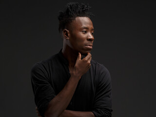 portrait of an African young man in a black shirt on a black background