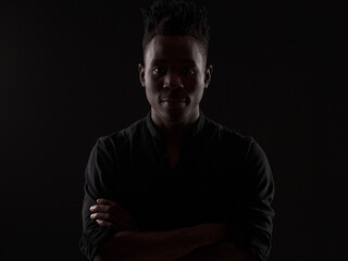 dramatic portrait of a young African man in a black shirt against a black background