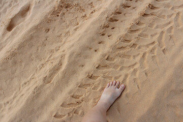 Foot of girl on white sand dunes with the tire traces in Mui Ne, Vietnam