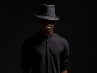 portrait of a young African man in a black hat. Black background studio photography