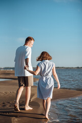 Couple in love on the beach.Young man and woman walking on seashore and laughing.