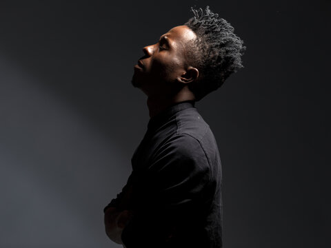 emotional portrait of a young African man in a black shirt against a black background