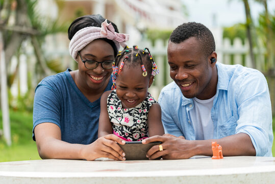 Happy and smile African family take selfie photo , play mobile game app or watch video by phone in outdoor garden togetter