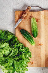 Fresh cucumbers and lettuce on a cutting board.