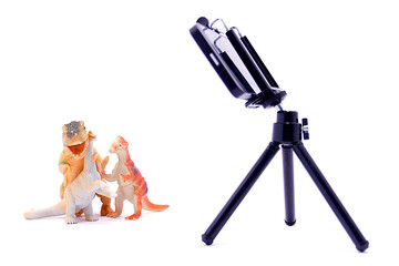 Dinosaur toys are photographed on a smartphone on a white background