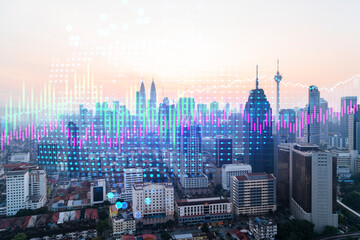 Market behavior graph hologram, sunset panoramic city view of Kuala Lumpur. KL is popular location to achieve financial degree in Malaysia, Asia. The concept of financial data analysis.