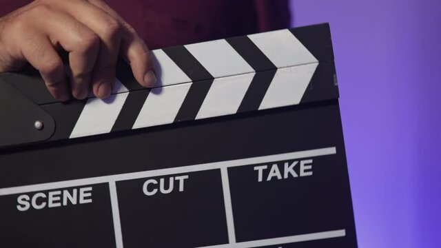 Clapboard on set. Director says action! and the clapboard close down. Cinema or photoshoot concept. Hollywood set with blue background. Close up shot