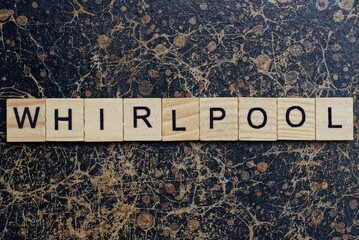 word whirlpool from wooden letters in black font on a brown shabby wall with a pattern