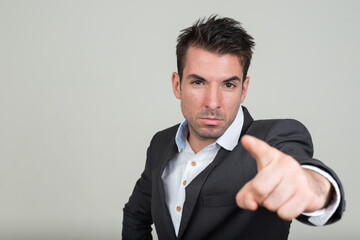 Portrait of young handsome Hispanic businessman in suit