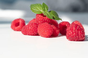 
Raspberries on a white plate and with mint in the middle.