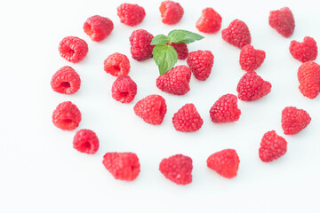 
Raspberries on a white plate and with mint in the middle.