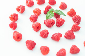 
Raspberries on a white plate and with mint in the middle.