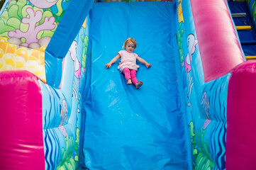 Cute blonde girl riding an inflatable slide.