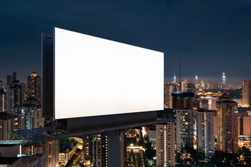 Blank white road billboard with KL cityscape background at night time. Street advertising poster, mock up, 3D rendering. Side view. The concept of marketing communication to promote or sell idea.