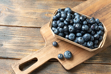 Blueberries in a wooden box on a brown wooden table. Fresh blueberries in a box. Top view with space for text