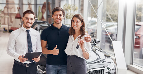 Happy clients and manager in car dealership
