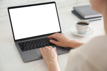 Woman working with modern laptop at white wooden table, closeup. Space for design