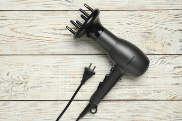 Hair dryer on white wooden table, top view. Professional hairdresser tool