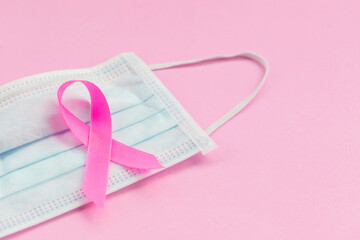 Breast Cancer concept : Top view pink ribbon and protective mask symbol of breast cancer campaign on pink