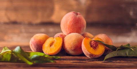 Orange peaches with green leaves on the wooden background. Sliced fruit, copy space.