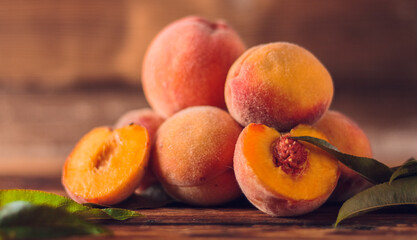 Orange peaches with green leaves on the wooden background. Sliced fruit, copy space.