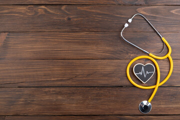 Workplace of a doctor. Stethoscope and little heart on wooden desk background