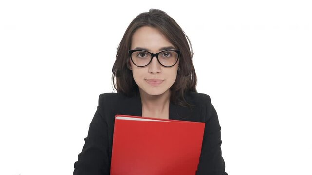 Portrait of young Caucasian woman in formal jacket holding red folder, putting up slipping glasses, doesn't know what to do. Expressing doubt. Isolated on white background