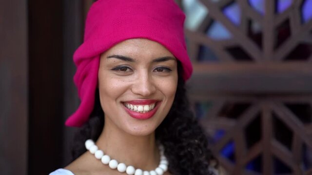 portrait of happy young black woman, smiling broadly, dressed in ethnic headscarf