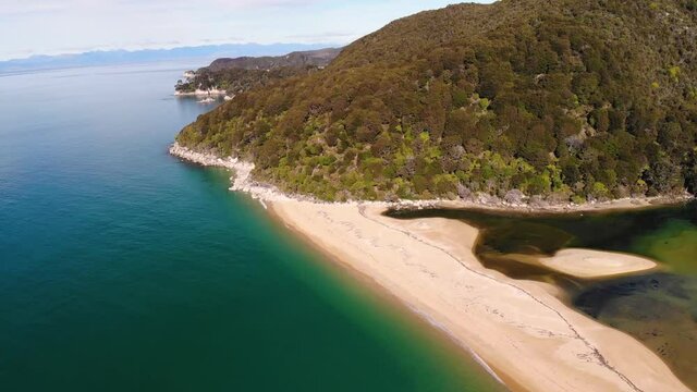 Jungle forrest covered mountain aerial fly forward shot. Birds eye of view from the seaside. Nature wild island of New Zealand.