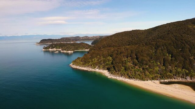 Shape of Abel Tasman Coast aerial orbit shot reveal of the small bay and sandy beach in contrast to jungle forrest. Nice colours during sunny day in New Zealand.