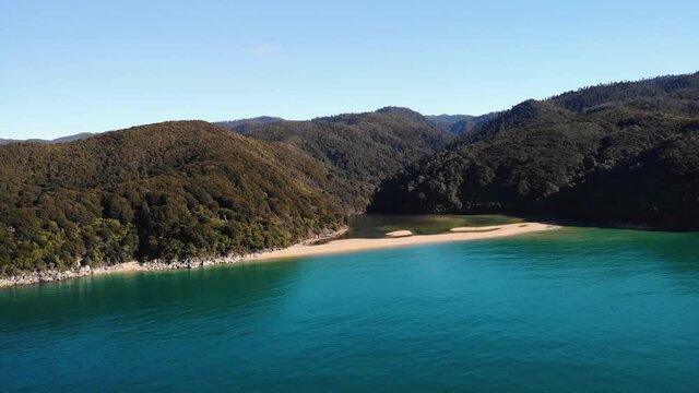 Sandfly bay in Abel Tasman aerial fly backward shot, reveal of New Zealand coast landscape. Warm day in paradise.