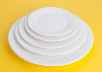 Stack of round white plates on yellow backgrown