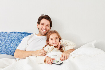 Glückliches Mädchen im Bett mit Fernbedienung