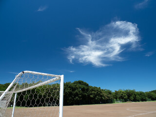 Fototapeta premium 真夏の青空と土のサッカーコートの風景