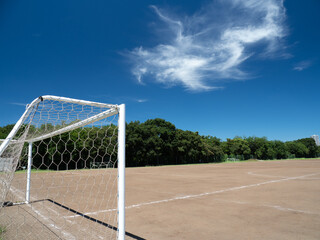 真夏の青空と土のサッカーコートの風景
