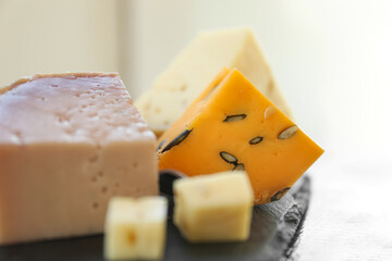 Different types of delicious cheeses on slate plate, closeup