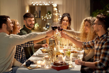 holidays, celebration and people concept - happy friends having christmas dinner at home drinking non-alcoholic red wine