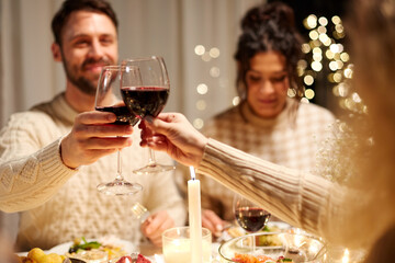 holidays, celebration and people concept - happy friends having christmas dinner at home drinking non-alcoholic red wine