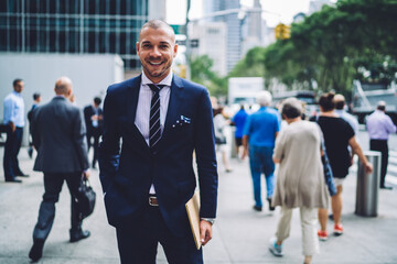 Obraz premium Half-length portrait of successful lawyer enjoying work and occupational strolling on crowded street, prosperous male entrepreneur in elegant suit looking at camera spending time outdoors in big city.