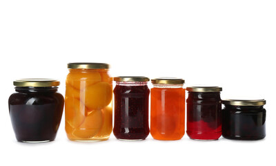 Glass jars with different pickled fruits and jams on white background