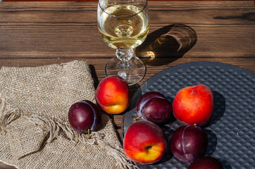 Glass with wine, peaches, plums and a napkin from a coarse cloth on the table close up