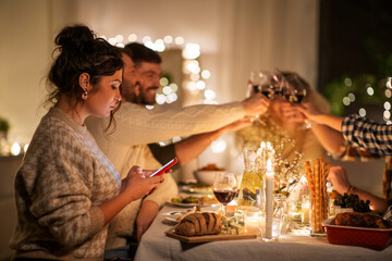 holidays and people concept - woman with smartphone at dinner party with friends at home